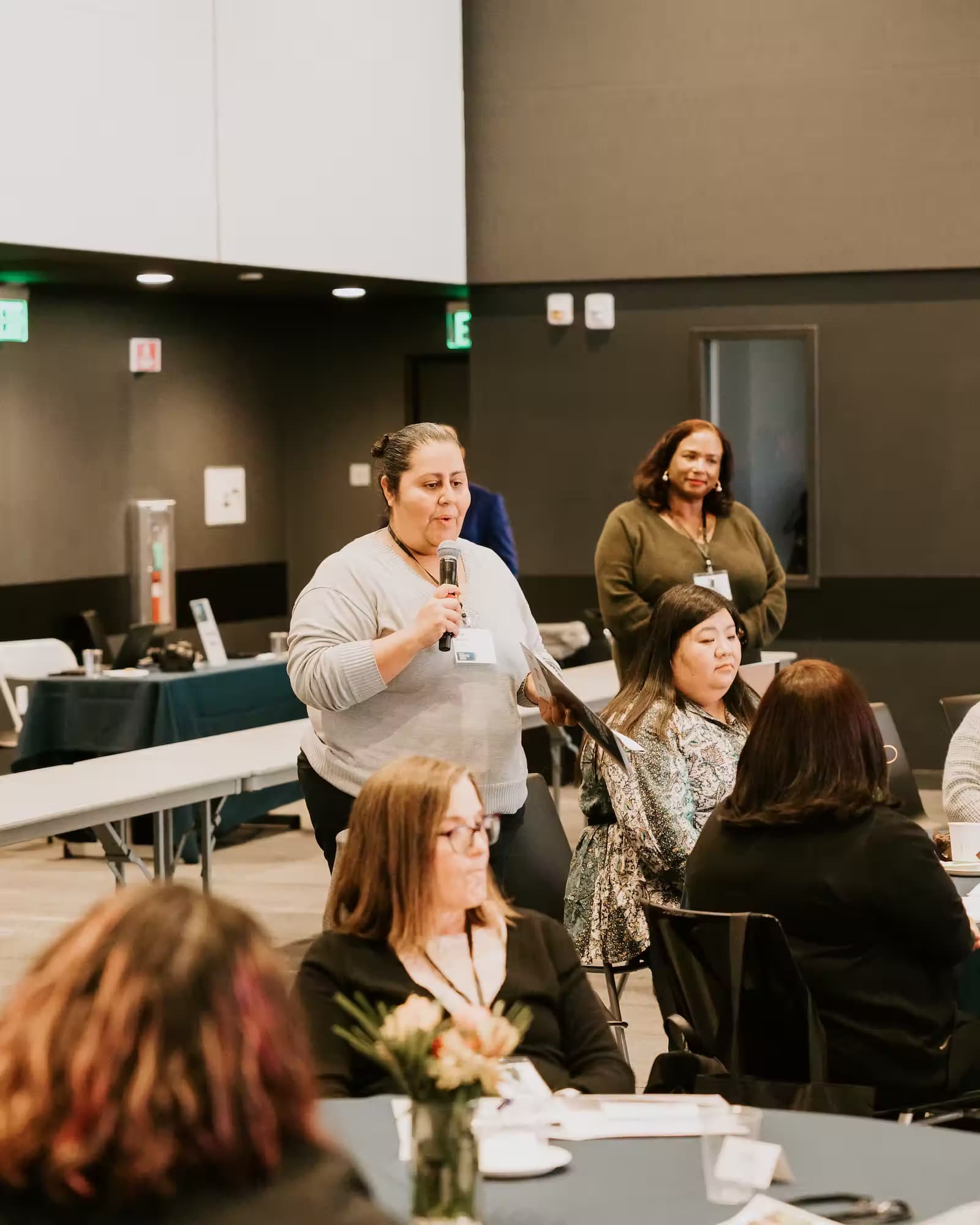 A woman addresses an audience at a conference, engaging with attendees through her speech and presentation.